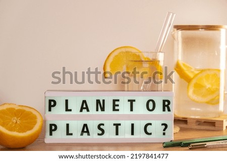 Lightbox with text PLASTIC OR PLANET Glass of water with fresh lemon juice with Reusable glass Straws Detox cold tonic water with sunny lemon slices Low-waste lifestyle Eco-Friendly Drinking Straw 