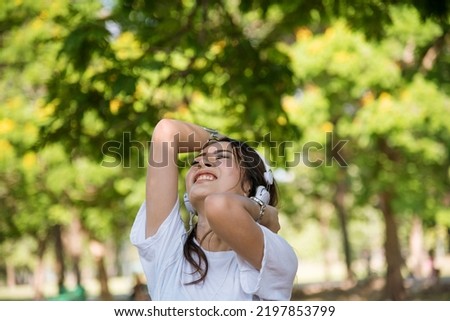 Leisure cheerful wellness woman Concept. Happy teenage woman listening to music wear headphones from smartphone outdoor in the park. Music mental therapist for wellness woman.