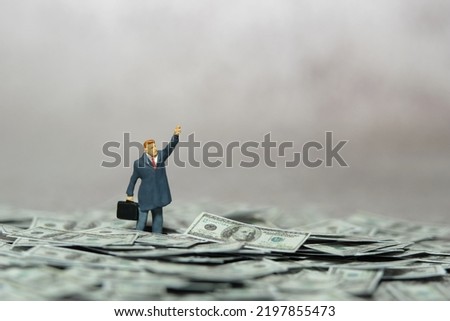 Miniature people figure toys photography. Inflation and recession concept. Businessmen standing above dollar money pile while raise his hand doing protest. Image photo