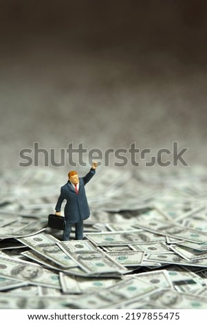 Miniature people figure toys photography. Inflation and recession concept. Businessmen standing above dollar money pile while raise his hand doing protest. Image photo