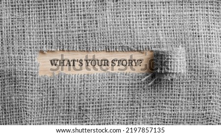 Monochrome image of a rough linen fabric with a torn window in the middle with a Whats your story? sign in it in real color. Top view.