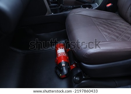 Small red fire extinguisher in the car to prevent an emergency.  fire safety equipment in car Royalty-Free Stock Photo #2197860433