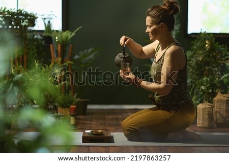 modern housewife with tea in the modern green living room. Royalty-Free Stock Photo #2197863257
