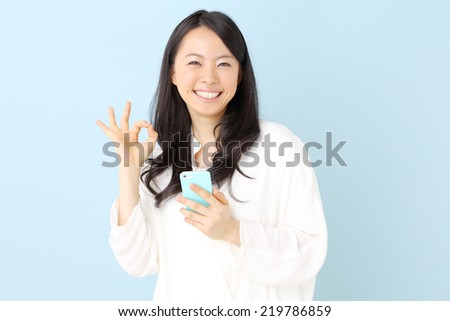 young beautiful girl using mobile phone, against blue background