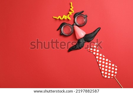 Funny face made with clown's accessories on red background, flat lay. Space for text