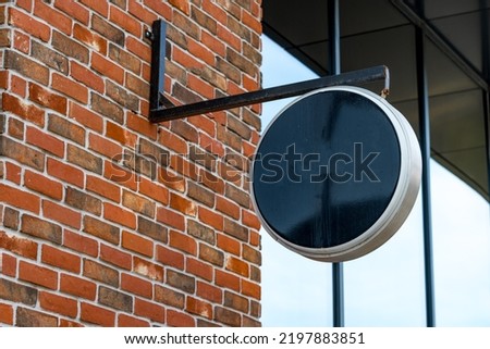 Empty black round signboard on the brick wall