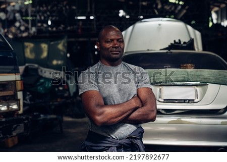 Portrait of man auto mechanic working at car repair shop with looking at camera.	