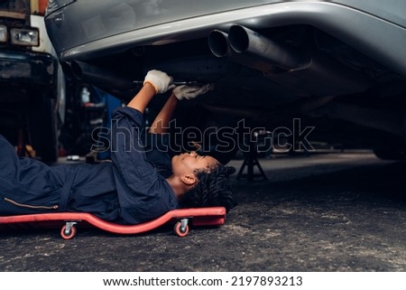 Auto mechanic are checking and repair maintenance underneath a car at the repair garage.