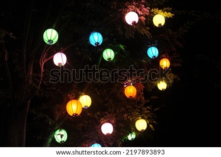 Colorful paper lantern lamps hanging on a tree at night and glowing light in the dark in Asia