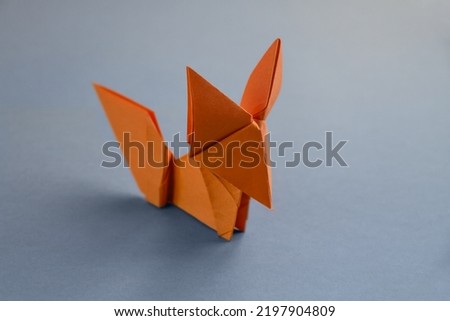 Orange paper fox origami isolated on a blank grey background.
