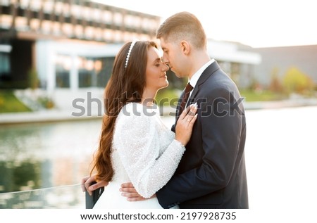 The newlyweds pose at sunset on the background of the lake