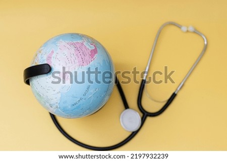 Globe and stethoscope on yellow background, world health day concept Stethoscope lying around globe on yellow background