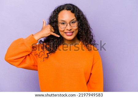 Young hispanic woman isolated on purple background showing a mobile phone call gesture with fingers.