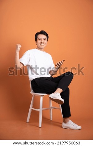 man sitting on chair  isolated on orange background Royalty-Free Stock Photo #2197950063