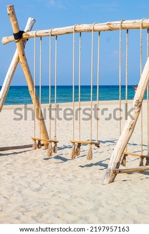 Swing on a beach with Tropical sea picture with tropical swing. Near sea. visible sea. Isolated swing made out of rope and wood