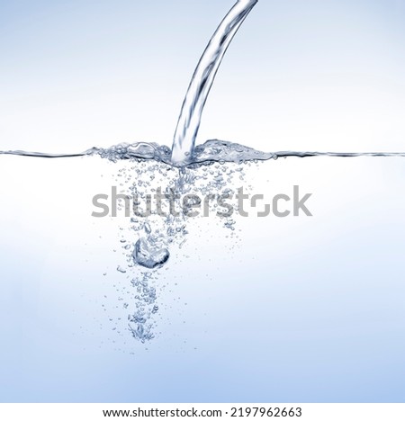 Waterjet puiring water against water surface on blue background Royalty-Free Stock Photo #2197962663