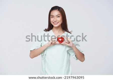 Happy asian woman patient showing heart isolated on white background. Insurance cardiovascular and cardiac concept.