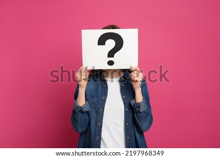 Woman holding question mark sign on pink background Royalty-Free Stock Photo #2197968349