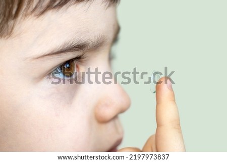 contact lens for kids,safe to wear.cute little boy putting one silicone contact lens,holding finger close up to the eye.vision correction,ophthalmology for children's concept.isolated space for text  Royalty-Free Stock Photo #2197973837