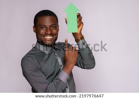 handsome african man holding an arrow pointing upwards
