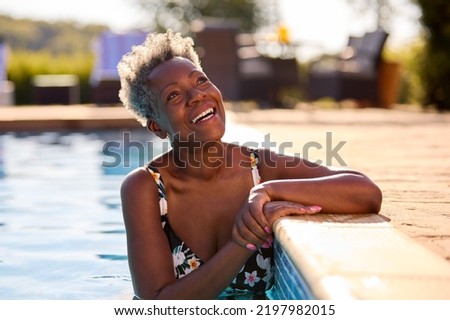 Smiling Senior Woman On Summer Holiday Relaxing In Swimming Pool