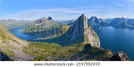 View from the mount Hesten on iconic mountain Segla in a summer sunny day. Mountain ranges at the background. Fjordgard, Senja island, Norway. Summer vacation in Lofoten                               Royalty-Free Stock Photo #2197982459