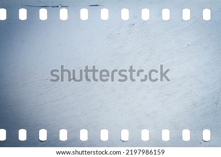 Dusty and grungy 35mm film texture or surface. Perforated scratched camera film isolated on white background. Royalty-Free Stock Photo #2197986159