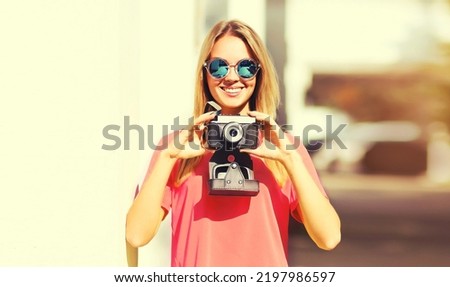 Portrait of happy young woman photographer with film camera in summer park