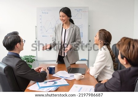 Asian businesspeople sit at desk in boardroom discuss financial paperwork at briefing, focused diverse colleagues brainstorm analyze ideas at team meeting in office, teamwork concept. Royalty-Free Stock Photo #2197986687