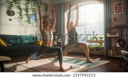 Athletic Young Couple Exercising Together, Stretching and Doing Yoga in the Morning in Bright Sunny Room at Home. Beautiful Man and Woman in Sports Clothes Practising Different Asana Poses on the Mat. Royalty-Free Stock Photo #2197992213