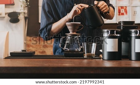 Professional barista making filtered drip coffee in coffee shop. Close up of hands barista brewing a drip hot espresso, pour over coffee with hot water and filter paper in cafe. Royalty-Free Stock Photo #2197992341