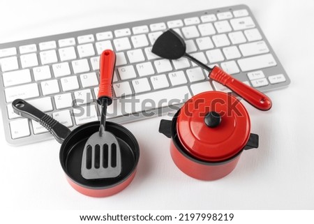 Keyboard and toy cooking utensils. Image of looking up recipes online