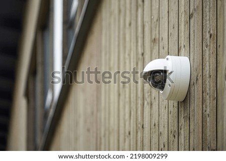 Round shaped weathersealed Security camera on the wooden wall
