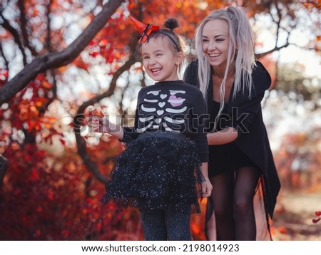 Mother and her child girl playing together. goes trick or treating. Little witch, Kids with jack-o-lantern. Children with candy bucket in fall forest. Happy Halloween.