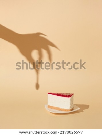 Halloween minimal concept with cheesecake and witch or zombie hand shadow. Creative spooky holiday fun background.