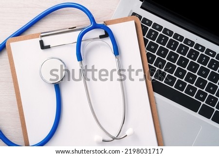 Doctor diagnoses design concept - stethoscope on computer keyboard with medical record clipboard on white working table.