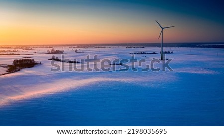 Wonderful snowy field and wind turbine at sunrise in winter, aerial view Royalty-Free Stock Photo #2198035695