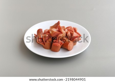 Slices of fried beef sausage served on plate isolated on light gray background