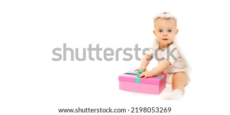 Happy cute baby playing with gift box toy sitting on the floor on white background