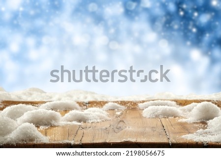 Wooden desk of free space cover of snow flakes and winter ladnscape. 