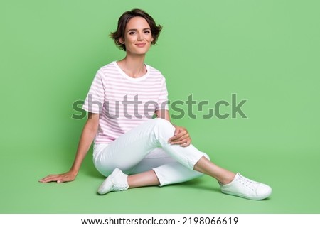 Photo of pretty cute lady dressed nice clothes outfit sit floor relax rest good mood free time isolated on green color background