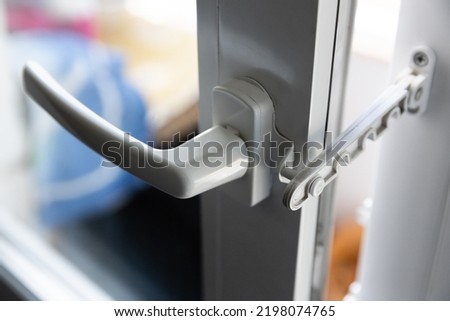 Close-up of a white pvc balcony door handle, an insulating glass window comb fixes the sash. Fittings for child protection and safe ventilation. Royalty-Free Stock Photo #2198074765