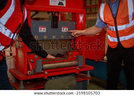 The manager is explaining the precautions and safety warning signs. attached to the machine for the engineering team in sheet steel factory Safety symbol concept in the work industry, engineering.