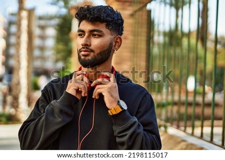 Young arab man smiling confident wearing headphones at street