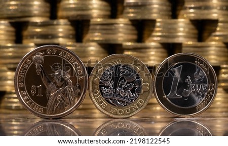 Coins of 1 American dollar, 1 British pound and 1 euro against the background of columns of gold coins
