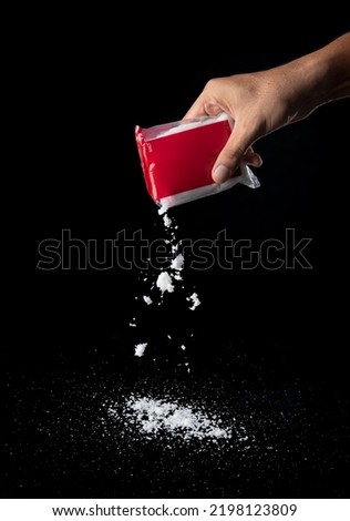 Salt pours from plastic bag isolated on black background,sprinkles salt
