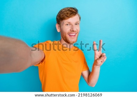 Photo of satisfied cool blogger bright smile trendy outfit make selfie picture show vi sign symbol empty space isolated on cyan color background