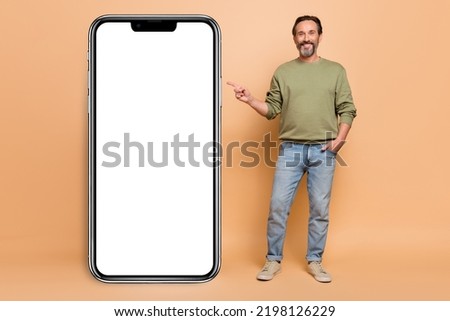 Full length portrait of cheerful friendly person indicate finger empty space blank isolated on beige color background