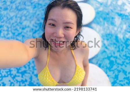 young happy and attractive Asian Korean woman enjoying relaxed and cheerful taking selfie photo in swimming pool at hotel resort in tourism travel concept