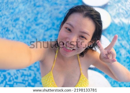 young happy and attractive Asian Korean woman enjoying relaxed and cheerful taking selfie photo in swimming pool at hotel resort in tourism travel concept